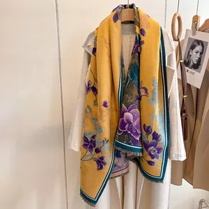 Close-up of elegant yellow floral scarf with purple orchid patterns and knit fringe details