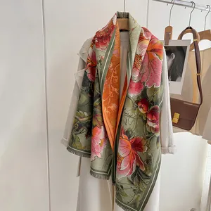 Close-up of elegant floral cashmere shawl with vintage fringe details on white coat