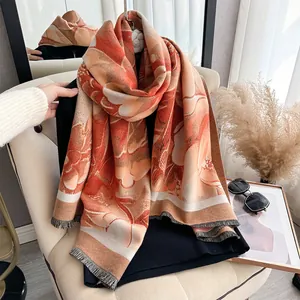 Close-up of floral cashmere feel scarf with tassel edges on a neutral sofa chair