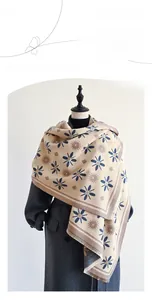 Detail of floral cashmere-like scarf with short fringe on grey coat
