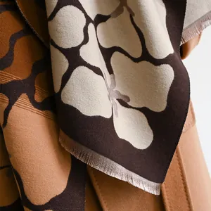 Detailed view of winter scarf fabric featuring floral jacquard pattern and soft fringe