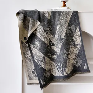 Détail macro du châle en tricot avec motif papillon, texture chevron et bords à franges