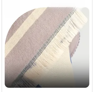 Detailed close-up of woven fabric texture and delicate fringe edge on a striped scarf