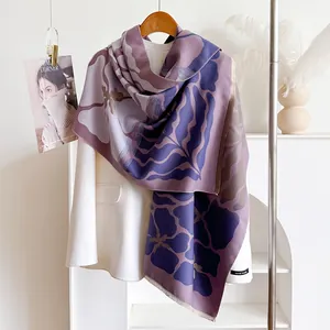 Detailed view of purple floral pashmina shawl draped over a creamy white autumn winter coat