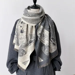 Détail du motif papillon et des franges sur l'écharpe châle grise en imitation cachemire