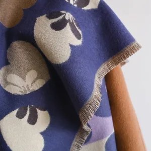 Close-up of soft navy knit scarf with heart floral patterns and fine short tassels