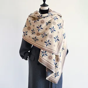 Detail of floral pattern cashmere-like scarf with fringe edges on a grey coat