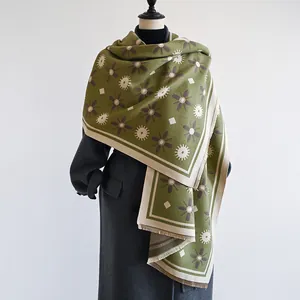 Detail of olive green cashmere-like scarf with floral star patterns and fringe
