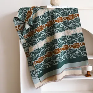 Détail d'une écharpe en maille avec motif à carreaux éléphant et longs pompons