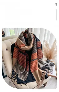 Detail of cashmere-like shawl with orange plaid pattern and long fringe tassels