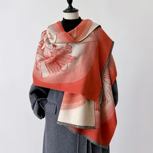 Dettaglio di scialle morbido effetto cashmere con motivi floreali arancioni e frange