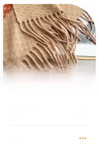 Macro detail of beige cashmere scarf featuring orange plaid patterns and fringe edges