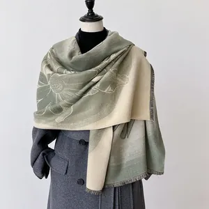 Scialle floreale verde e beige in cashmere con frange indossato su un cappotto grigio