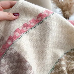 Detailed macro view of soft cashmere-like knit fabric with pink and cream plaid pattern