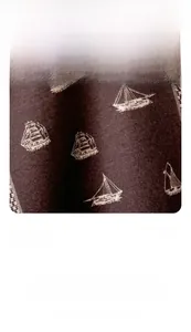 Detailed macro view of dark coffee fabric featuring white sailboat print and woven texture