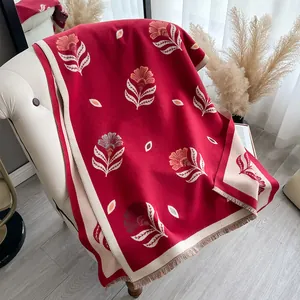Close-up of red cashmere-feel scarf featuring floral embroidery and tassel details