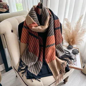 Detail of soft plaid cashmere-feel scarf with orange and brown check and fringe trim