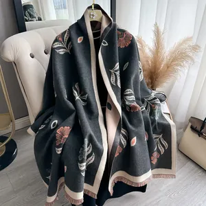 Detail of floral cashmere-feel shawl with elegant tassels on a neutral lounge chair