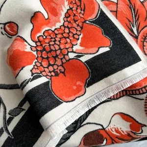 Detailed macro view of vibrant pomegranate floral patterns and soft fringe on the winter scarf