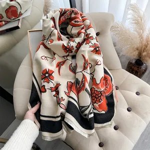 Detail of soft pomegranate jacquard knit scarf with red floral patterns and tassel edges