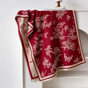Detail of burgundy cashmere shawl showing white floral embroidery and tassel fringe edges