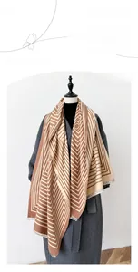 Detailed view of cashmere-feel scarf with geometric stripes and fringe on grey coat
