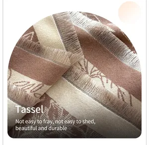 Detail view of the thick fringe edges and jacquard leaf pattern on a cashmere-like scarf