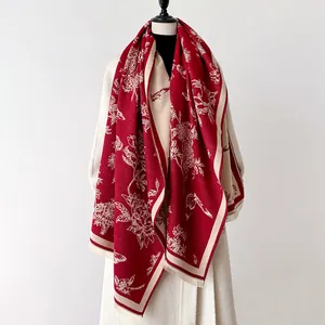 Macro detail of wine red faux cashmere scarf with cream floral patterns and fringe