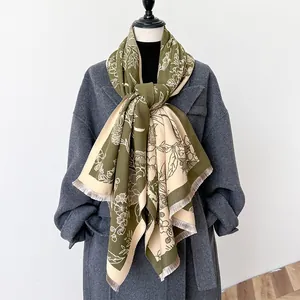 Detail of floral cashmere-like scarf with tassels on olive green and beige shawl