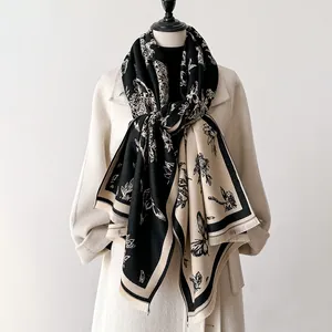 Detailed close-up of cashmere-like floral scarf featuring butterfly prints and soft tassels