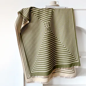 Detail of green and beige cashmere-like scarf with geometric patterns and fringe