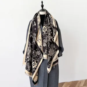 Elegant floral cashmere-feel shawl with fringe in black and beige, draped over a grey coat