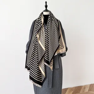 Detail of geometric stripe pashmina shawl draped on mannequin over grey wool coat
