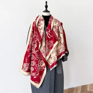 Detail of red floral cashmere-style shawl with fringes over a dark gray coat