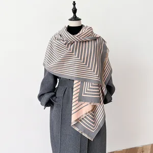 Detail of color-block geometric scarf with soft tassels on a grey wool coat