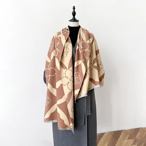 Two-tone geometric floral scarf in brown and beige with fringe on a grey coat