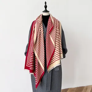 Detail of red and beige geometric stripe scarf with tassels on grey winter wool coat