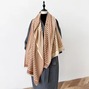 Geometric stripe cashmere shawl in brown and beige colors with fringe edge on coat