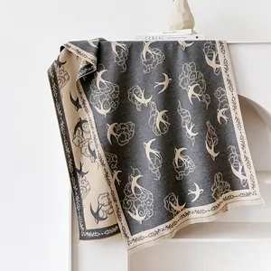 Detail of grey and beige cashmere-feel scarf featuring swallow and cloud jacquard patterns
