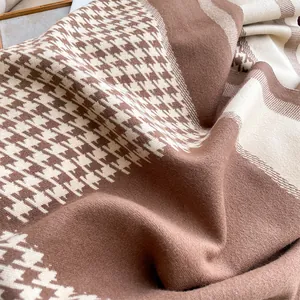 Detailed close-up of thick houndstooth knit fabric texture in brown and beige tones