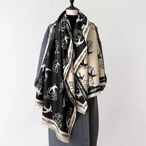 Detail of cashmere-like scarf showing flying swallows and clouds pattern with fringe trim