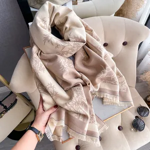 Close-up of elegant bamboo leaf print scarf with fringe edge on a beige armchair