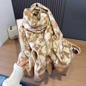 Detail van beige en camel jacquard sjaal met geometrische patronen en fijne franjes