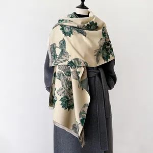 Detail van imitatie kasjmier sjaal met vintage bloemenprint en franjes op grijze jas