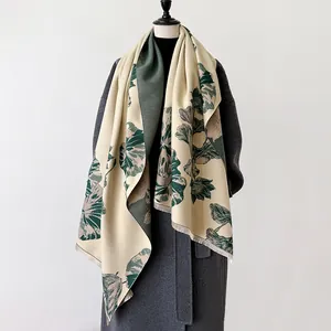 Detail van oversized sjaal met botanische print en franjes en print op een donkere wollen jas