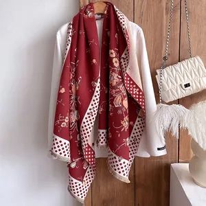 Detail of red floral scarf with retro print, polka dots, and fringe edges on a white coat