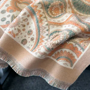 Detailed view of paisley patterns and tassel fringes on the orange textile shawl