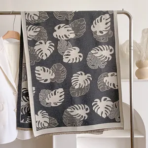 Détail d'écharpe en maille avec motif feuilles, bordures à franges et texture douce