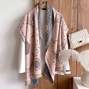 Close-up of pink and grey cashmere-like scarf with camellia patterns and fringe details