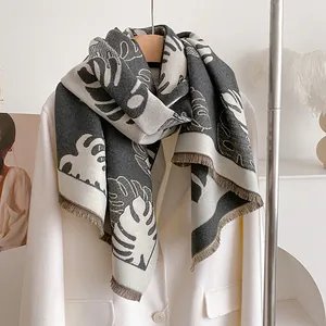 Détail d'une écharpe en maille jacquard à feuilles et franges sur un blazer blanc
